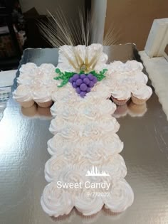 a cross made out of cupcakes on top of a table with wheat and grapes