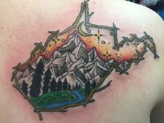 the back of a woman's shoulder with mountains and trees tattoo on her left side