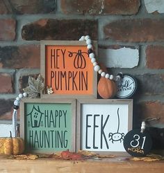 there are three wooden signs on the mantle with pumpkins and other decorations around them