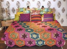 a bed with colorful crocheted bedspread and pillows on top of it