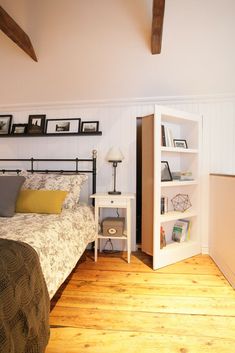 a bed room with a neatly made bed and a book shelf on the wall next to it