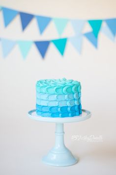 a blue cake sitting on top of a white cake platter next to bunting