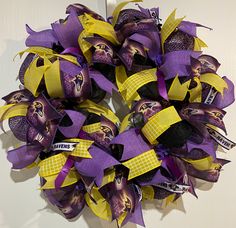 a wreath with purple and yellow ribbons on the front door is decorated with footballs