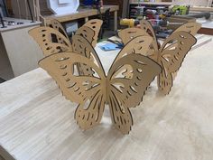 some cut out butterflies sitting on top of a wooden table in a room filled with tools