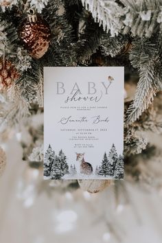 a baby shower is hanging on a christmas tree with pine cones and ornaments around it