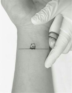 a small panda bear tattoo on the wrist