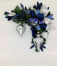 a blue and white christmas decoration with two silver heart shaped ornaments hanging from it's side