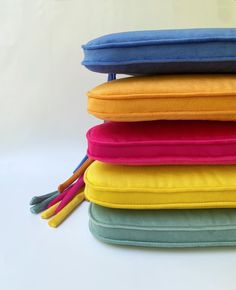 four different colored pillows stacked on top of each other with tassels attached to them