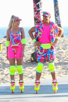 two people standing on roller skates in neon colored clothing and knee pads at the beach