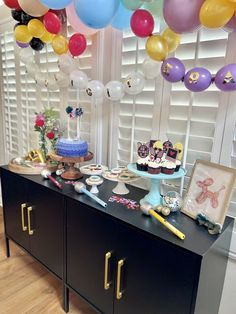 a buffet with balloons and cake on it