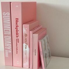 three pink books are stacked on top of each other in front of a white wall