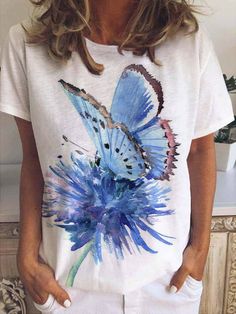 a woman wearing a white t - shirt with a blue butterfly painted on the front