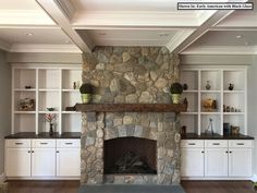 a living room with a stone fireplace and white cabinets