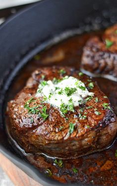 two steaks are cooking in a skillet with sauce and sour cream on top