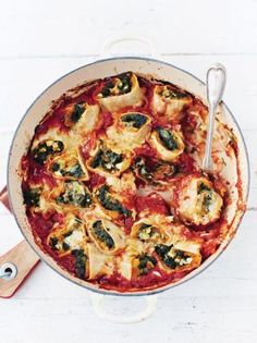 a pan filled with pasta and spinach covered in sauce