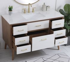 a bathroom vanity with drawers and a mirror on the wall next to potted plant