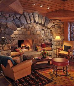 a living room filled with furniture and a fire place next to a stone wall covered in rocks