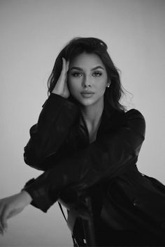 a black and white photo of a woman in a leather jacket leaning on a chair