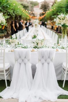 the chairs are covered with white chiffon sashes and bows at the head table