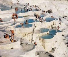 many people are swimming and playing in the water at an outdoor pool that is covered with snow