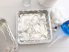 two metal pans sitting on top of a table next to cotton balls and toothbrushes