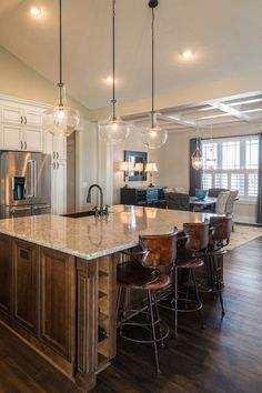 a large kitchen with an island in the middle and lots of lights hanging from the ceiling