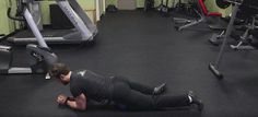 a man laying on the ground in a gym with machines and other equipment behind him