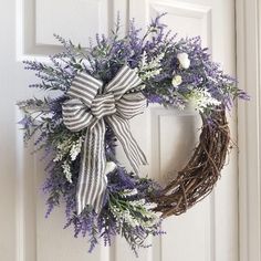 a wreath with purple and white flowers hanging on the front door to give it an elegant touch