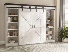 an open bookcase with sliding doors in a living room next to a potted plant