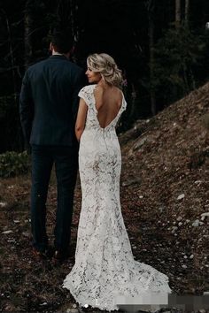 a bride and groom standing in the woods looking at each other with their back to the camera