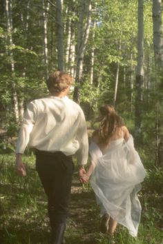 a man and woman are walking through the woods