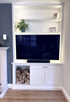 there is a television on the wall in the living room with firewood stacked under it