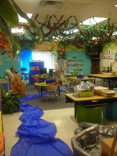 an empty classroom with blue tarps on the floor and desks covered in plastic