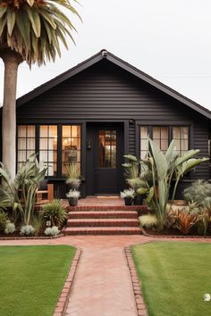 a black house with some plants in the front yard and steps leading to the door