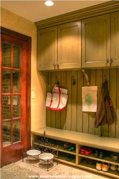 a wooden bench with shoes on it in front of a door and some cupboards