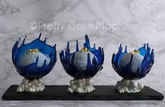 three blue glass vases sitting on top of a black marble slab in front of a marble wall