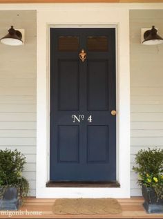 a blue front door with two potted plants on either side and the number 4