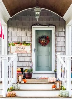 a front porch decorated for fall with pumpkins and gourds on the steps