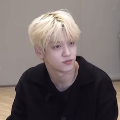 a young man with blonde hair sitting down