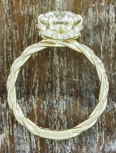 a yellow gold ring with an oval cut diamond in the center on top of a wooden surface