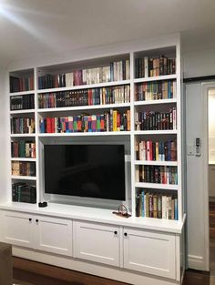 a living room with bookshelves and a flat screen tv mounted on the wall