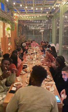 a group of people sitting at a long table with food and drinks in front of them