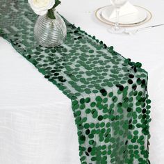 the table is set with a white rose and green sequins on it's edge