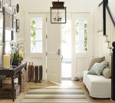 an entry way with a white couch and some pictures on the wall next to it