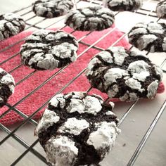 chocolate crinkle cookies cooling on a wire rack with red cloth and white powdered sugar