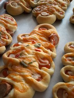 many small pizzas are lined up on a baking sheet and ready to be baked