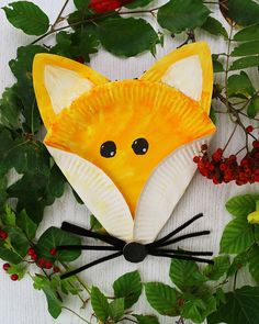 a paper plate shaped like a fox surrounded by leaves and berries