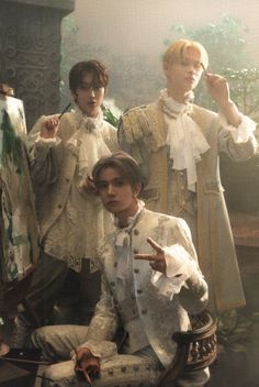 three young men dressed in period clothing standing next to each other and pointing at something