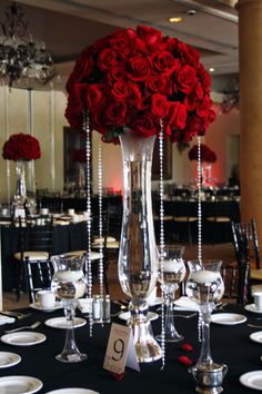 a vase filled with red roses sitting on top of a table covered in white plates