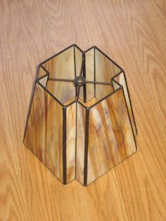 a stained glass candle holder sitting on top of a wooden table next to a wood floor